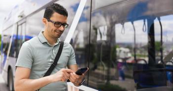 Homme consultant son téléphone intelligent à un arrêt d'autobus