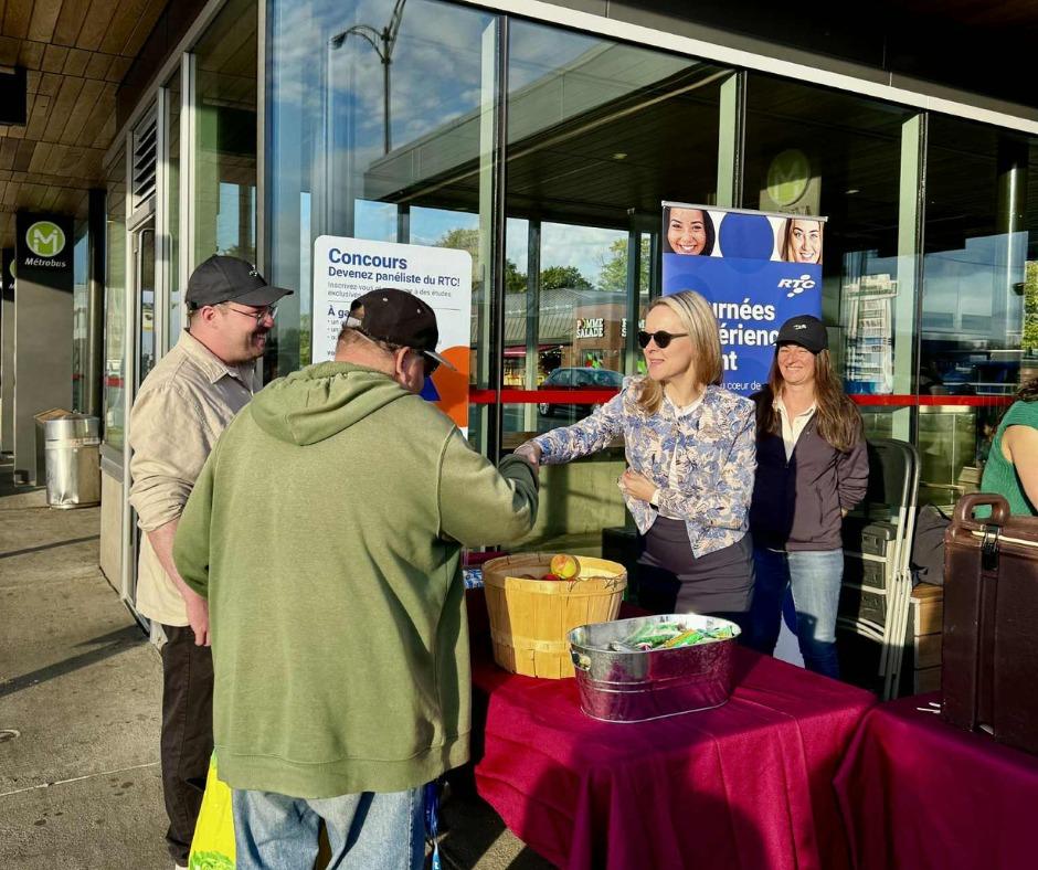 Des employés du RTC discutent avec des clients à un kiosque. 