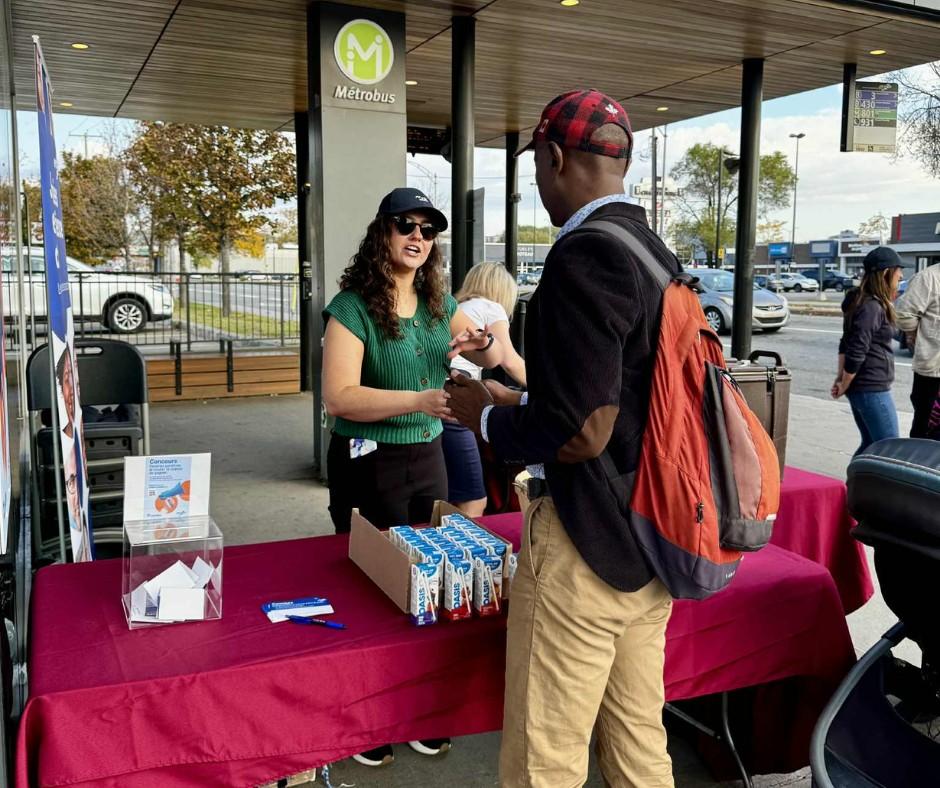 Des employés du RTC discutent avec des clients à un kiosque. 